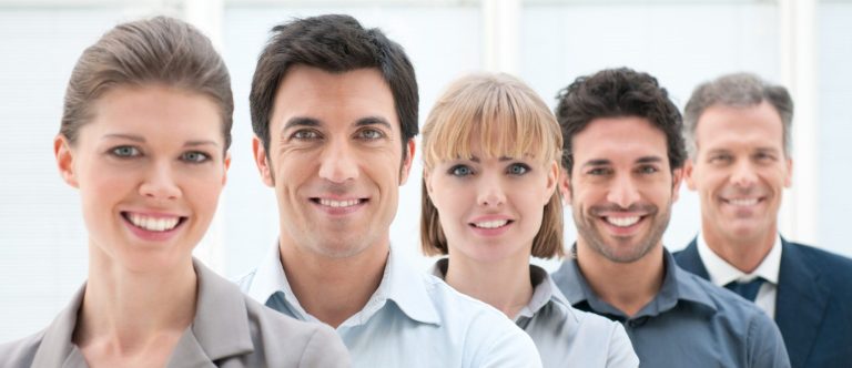 A row of five people all smiling dressed smartly